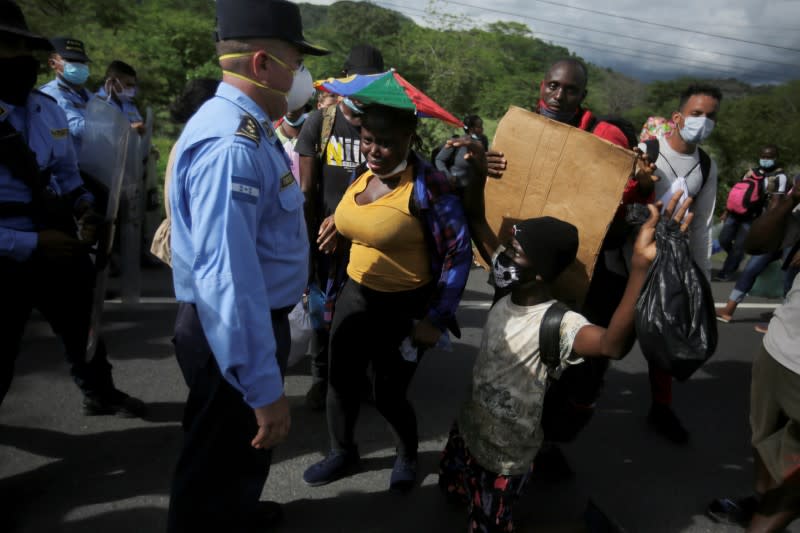 Migrants from Africa, Cuba and Haiti, who are stranded in Honduras after borders were closed due to the coronavirus (COVID-19) pandemic, block a road as police officers look on while trekking northward in an attempt to reach the U.S., in Choluteca