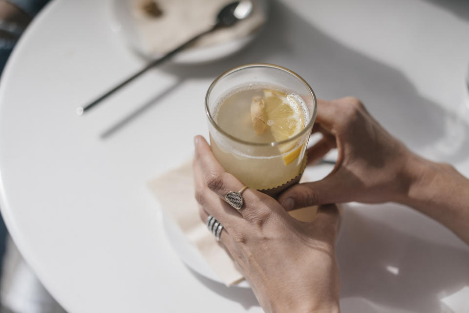 Woman holding glass of ginger lemon tea