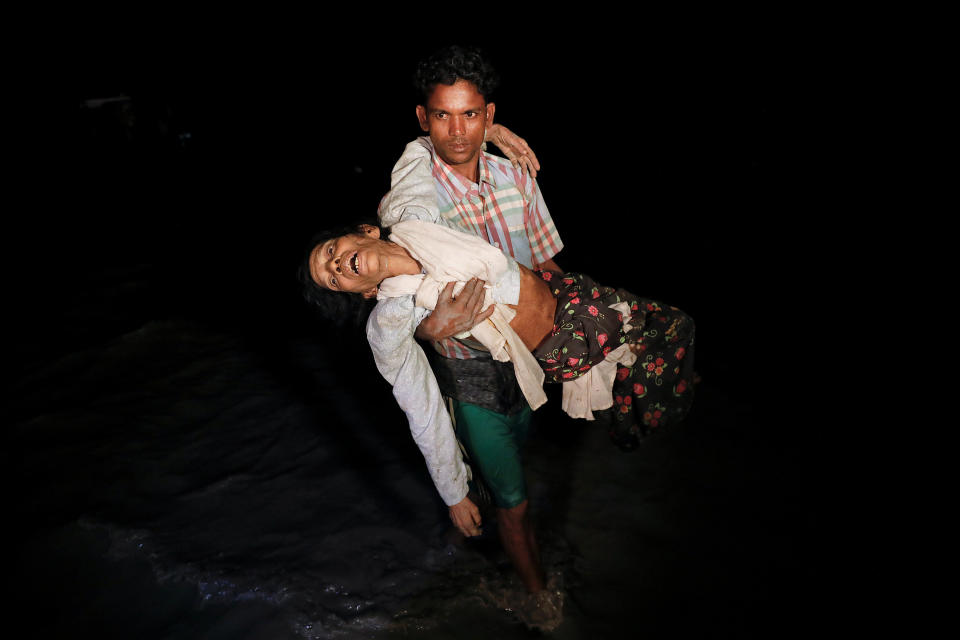 Nobi Hossain wades through the water carrying his elderly relative, Sona Banu, as hundreds of Rohingya refugees arrive by wooden boats from Myanmar to the shore near Cox's Bazar in Bangladesh, on Sept. 27. (Photo: Damir Sagolj/Reuters)