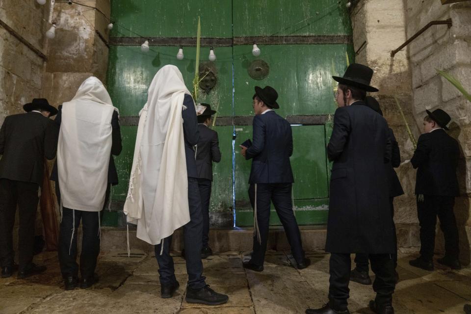 Jewish worshippers pray during the weeklong Jewish holiday of Sukkot, next to one of the gates to the Temple Mount, known to Muslims as the Noble Sanctuary, or the Al-Aqsa Mosque compound, in the Old City of Jerusalem, Wednesday, Oct. 4, 2023. (AP Photo/Ohad Zwigenberg)