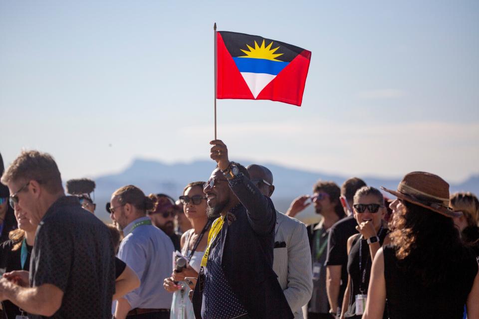 A spectator waves a flag of Antigua and Barbuda during the Galactic 02 Launch on Thursday, August 10, 2023, at Spaceport America. Two of the passengers, Keisha Schahaff and Anastatia Mayers, are from Antigua and Barbuda.