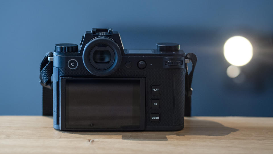 Leica SL3 camera on a wooden surface against a blue background