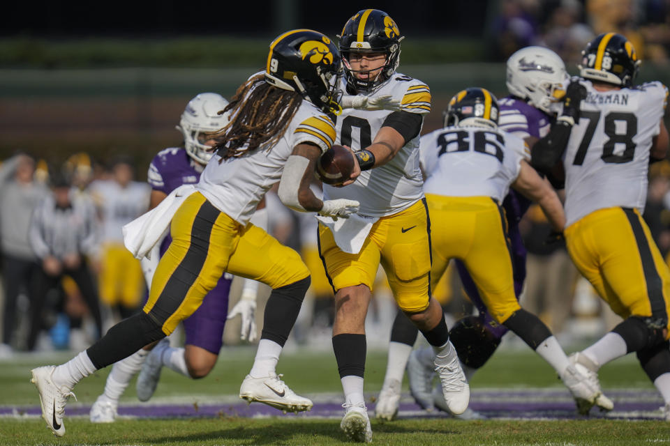 Iowa quarterback Deacon Hill, center, hands off the ball to running back Leshon Williams, front left, during the first half of an NCAA college football game against Northwestern, Saturday, Nov. 4, 2023, at Wrigley Field in Chicago. (AP Photo/Erin Hooley)