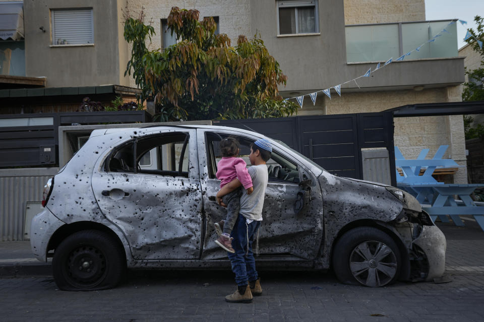 Israeli kids look at a car hit by a rocket fired from the Gaza Strip, at the southern Israeli city of Sderot, Tuesday, May 2, 2023. The Israeli military says that Palestinian militants in Gaza have fired a barrage of rockets following the death of Khader Adnan, a high-profile Palestinian prisoner in Israeli custody after a nearly three-month-long hunger strike. (AP Photo/Ohad Zwigenberg)