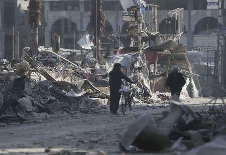 Men walk through a damaged area after what activists said were at least 20 air strikes by forces loyal to Syria's President Bashar al-Assad in the Douma neighbourhood of Damascus February 5, 2015. REUTERS/ Bassam Khabieh