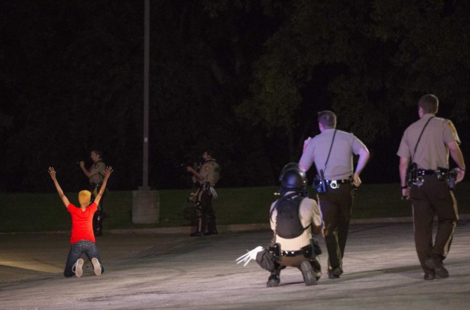 <p>Police officers briefly detain a person in Ferguson, Missouri August 13, 2014. Police in Ferguson fired several rounds of tear gas to disperse protesters late on the fourth night of demonstrations over the fatal shooting of an unarmed black teenager Michael Brown, 18, by a police officer on August 9, after what police said was a struggle with a gun in a police car. A witness in the case told local media that Brown had raised his arms to police to show that he was unarmed before being killed. (Mario Anzuoni/Reuters) </p>