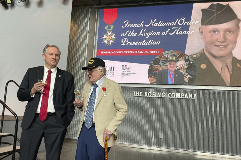 Ambassador of France to the U.S. Laurent Bili, Left, holds a glass of wine while talking with WWII veteran Samuel Meyer, 99, who was awarded with the rank of chevalier, or knight, in the French Legion of Honor, on Tuesday, Feb. 27, 2024, at the National WWII Museum in New Orleans. (AP Photo/Kevin McGill)