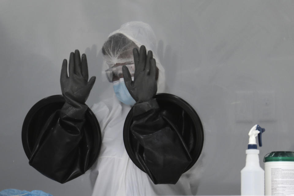 A health care worker air dries her gloves after sanitizing her equipment while working at a walk-up COVID-19 testing site during the coronavirus pandemic, Friday, July 17, 2020, in Miami Beach, Fla. The mobile testing truck is operated by Aardvark Mobile Health, which has partnered with the Florida Division of Emergency Management. People getting tested are separated from nurses via a glass pane. (AP Photo/Lynne Sladky)