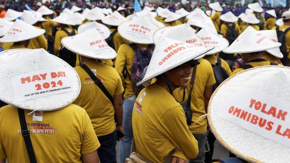Labourers wearing yellow t-shirts and white conical sun hats attend a protest during a May Day rally in Jakarta, Indonesia.