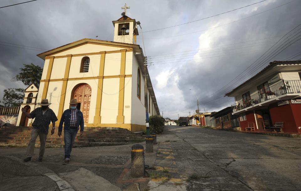 Men wearing masks to curb the spread of the new coronavirus, walk in Campohermoso, Colombia, Thursday, March 18, 2021. According to the Health Ministry, Campohermoso is one of two municipalities in Colombia that has not had a single case of COVID-19 since the pandemic started one year ago. (AP Photo/Fernando Vergara)