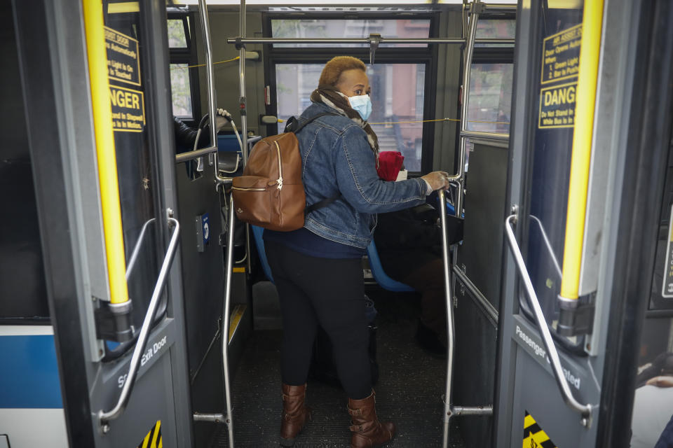 In this Thursday, April 23, 2020 photo, Ruth Caballero, a nurse with The Visiting Nurse Service of New York, rides a bus to a patient's home as she makes her rounds in upper Manhattan in New York. Home care nurses, aides and attendants, who normally help an estimated 12 million Americans with everything from bathing to IV medications, are now taking on the difficult and potentially dangerous task of caring for coronavirus patients. (AP Photo/John Minchillo)