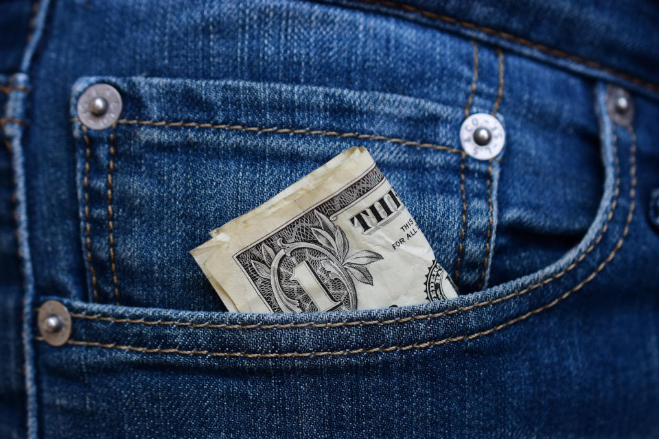 A folded dollar bill tucked into the front pocket of a pair of jeans.