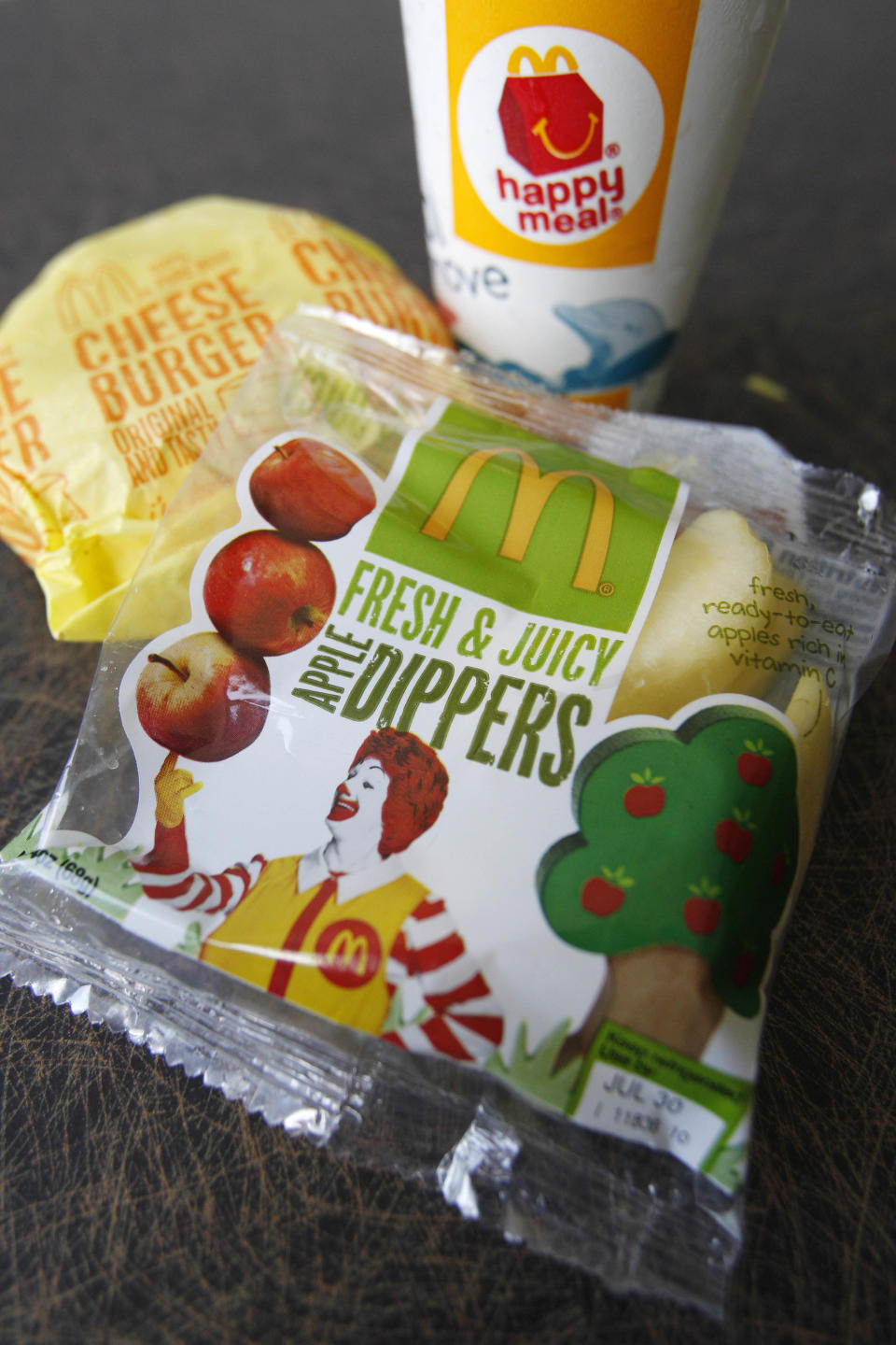 FILE - This July 26, 2011 file photo shows a McDonald's Cheeseburger Happy Meal with the new apple slices option in Pittsburgh. McDonald's Corp. says it is adding apple slices to every Happy Meal, part of the chain's larger push to paint itself as a healthy place to eat. McDonald's, Dunkin' Donuts and other fast-food chains have made a point of adapting their menus in recent years to better reflect shifting tastes. That has led to an uptick in offerings designed to appeal to health-conscious diners and parents, whether they're apple slices in Happy Meals, egg whites for breakfast sandwiches or whole grain breads. (AP Photo/Keith Srakocic, File)