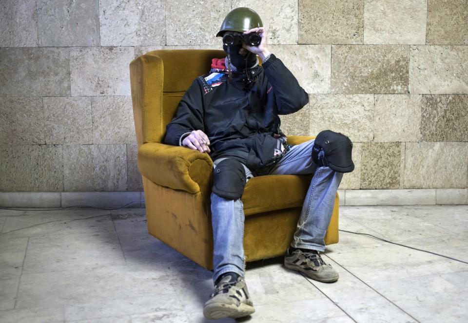 A masked pro-Russian protester poses with a pair of binoculars inside a regional government building in Donetsk