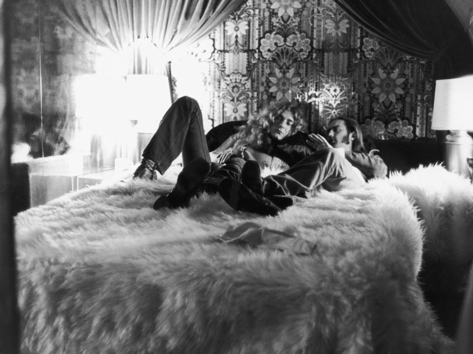 Led Zeppelin manager Richard Cole and singer Robert Plant sit on the white fur bedspread on the Starship.