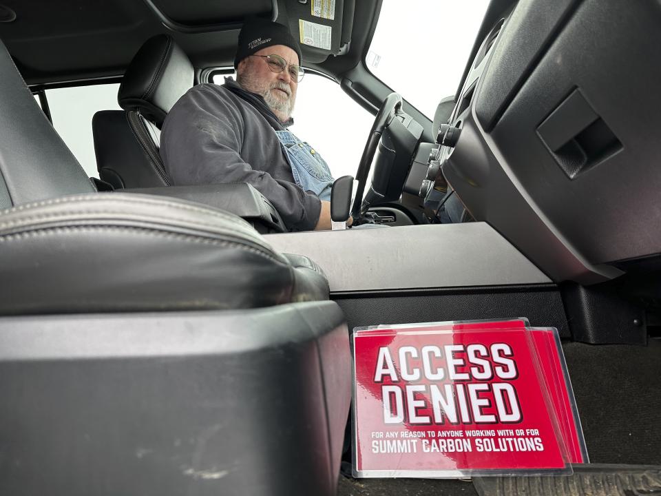 Dan McLean looks down at a sign that reads "Access denied for any reason to anyone working with or for Summit Carbon Solutions," in his truck on Wednesday, March 6, 2024, on his farm near Menoken, N.D. Summit Carbon Solutions has proposed a multistate carbon dioxide pipeline that would bury CO2 deep underground in North Dakota. The project has drawn opposition from many Midwestern landowners. (AP Photo/Jack Dura)