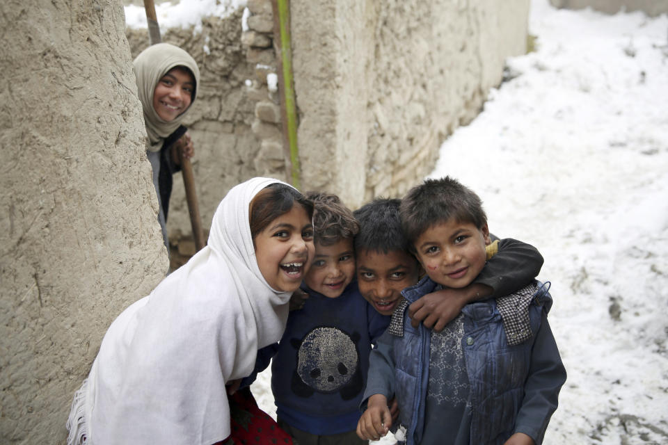 Internally displaced Afghan boys and girls pose for a photograph after a snowstorm at a camp on the outskirts of Kabul, Afghanistan, Sunday, Jan. 12, 2020. Kabul has been experiencing below freezing weather and snow. (AP Photo/Rahmat Gul)