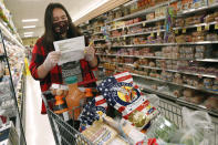 Alexandra Lopez-Djurovic checks her shopping list as she shops for a client in an Acme supermarket, Wednesday, July 1, 2020, in Bronxville, N.Y. Lopez-Djurovic was working full time as a nanny until her hours were cut substantially due to the coronavirus pandemic, so she started her own grocery delivery service that made up for some of her lost wages, but not all. (AP Photo/Kathy Willens)