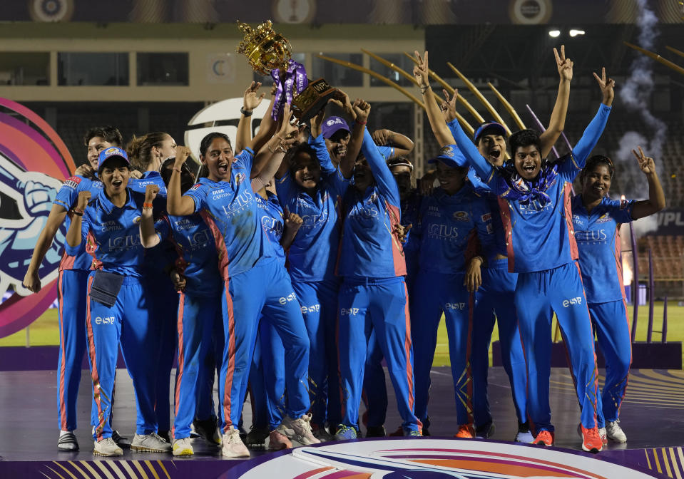 Members of Mumbai Indians team pose with the trophy after their win over Delhi Captials in the Women's Premier League Twenty20 cricket final in Mumbai, India, Sunday, March 26, 2023. (AP Photo/Rajanish Kakade)