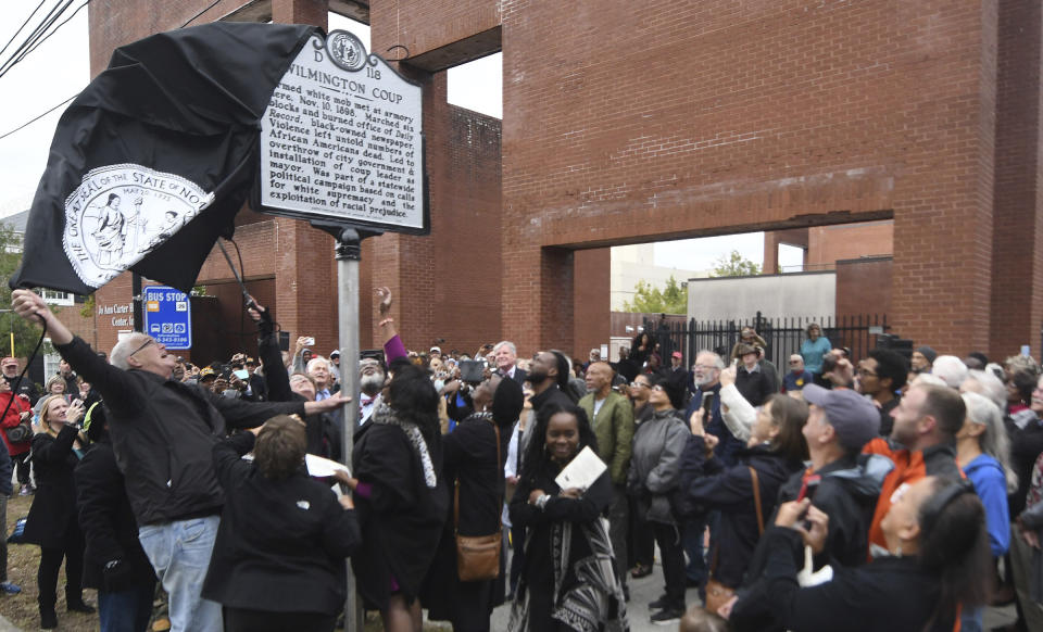 The new North Carolina highway historical marker to the 1898 Wilmington Coup is unveiled during a dedication ceremony in Wilmington, N.C., Friday, Nov. 8, 2019. The marker stands outside the Wilmington Light Infantry building, the location where in 1898, white Democrats violently overthrew the fusion government of legitimately elected blacks and white Republicans in Wilmington. (Matt Born/The Star-News via AP)