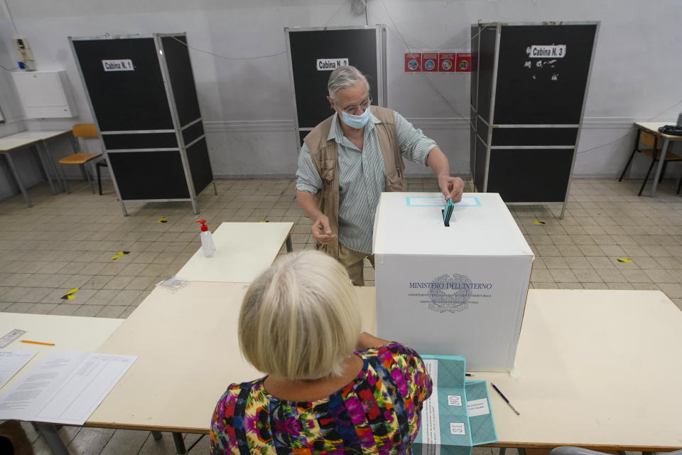 A man casts his ballot at a polling station, in Rome, Sunday, Sept. 20, 2020. On Sunday and Monday Italians are called to vote nationwide in a referendum to confirm a historical change to the country's constitution to drastically reduce the number of Members of Parliament from 945 to 600. Eighteen million of Italian citizens will also vote on Sunday and Monday to renew local governors in seven regions, along with mayors in approximately 1,000 cities. (AP Photo/Andrew Medichini)