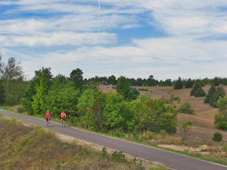 In this undated photo released by Traverse City Convention & Visitors Bureau, bicyclists cruise along the Leelanau Trail near Traverse City, Mich., a converted railroad corridor that winds past open fields, cherry orchards and woodlands. (AP Photo/Traverse City Convention & Visitors Bureau)