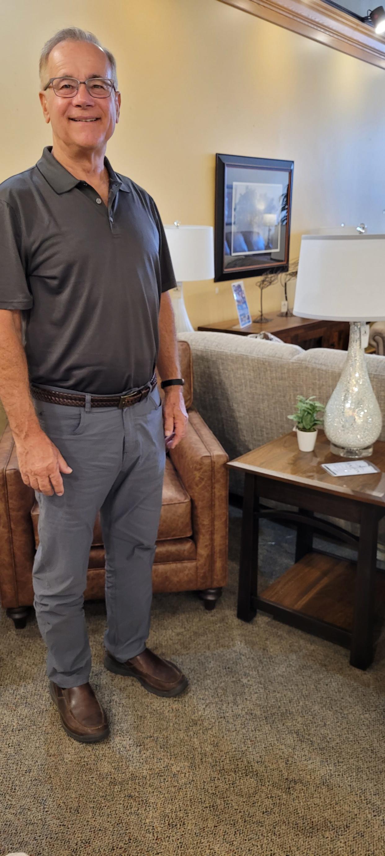 Founded selling strictly Amish-made solid wood furniture, Chris Tuttle says today Amish Oak in Loudonville sells many types of furniture, posing here with some of them in the Loudonville store. Tuttle, who founded Amish Oak in 1982, retired from the business last week.