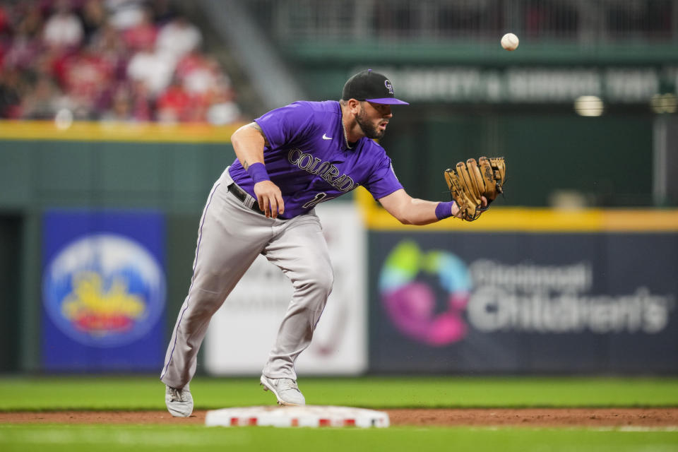 Colorado Rockies' Mike Moustakas commits a fielding error on a ball hit by Cincinnati Reds' Jonathan India during the sixth inning of a baseball game in Cincinnati, Monday, June 19, 2023. (AP Photo/Aaron Doster)