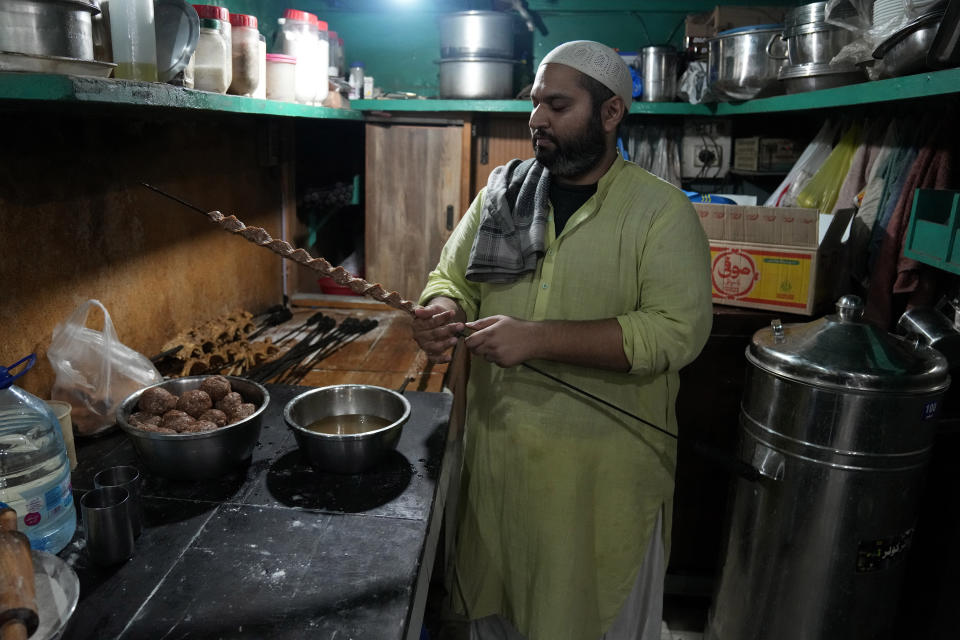 Bilal Sufi, owner of Baking Virsa eatery, prepares kebabs in Lahore, Pakistan, Saturday, Dec. 3, 2022. No menu. Baking Virsa, a hole-in-the-wall in the eastern Pakistani city of Lahore described as the country's most expensive restaurant for serving household favorites like flatbreads and kebabs at exorbitant prices. (AP Photo/K. M. Chaudary)