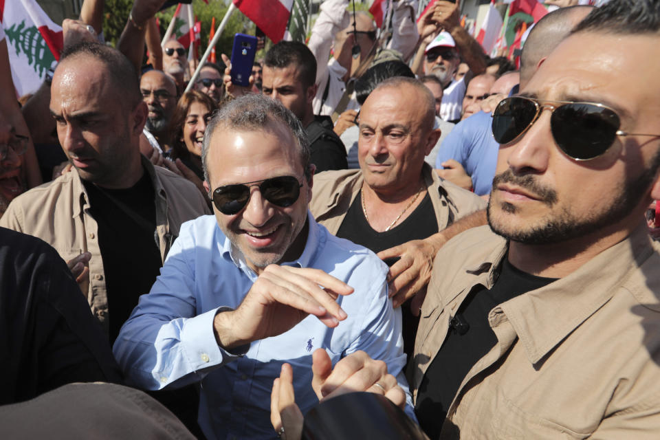 Head of the Free Patriotic Movement and Lebanese Foreign Minister Gebran Bassil, center, escorted by his bodyguards, greets supporters during a protest near the presidential palace in the Beirut suburb of Baabda, Lebanon, Sunday, Nov. 3, 2019. Thousands of people are marching to show their support for Aoun and his proposed political reforms that come after more than two weeks of widespread anti-government demonstrations. (AP Photo/Hassan Ammar)