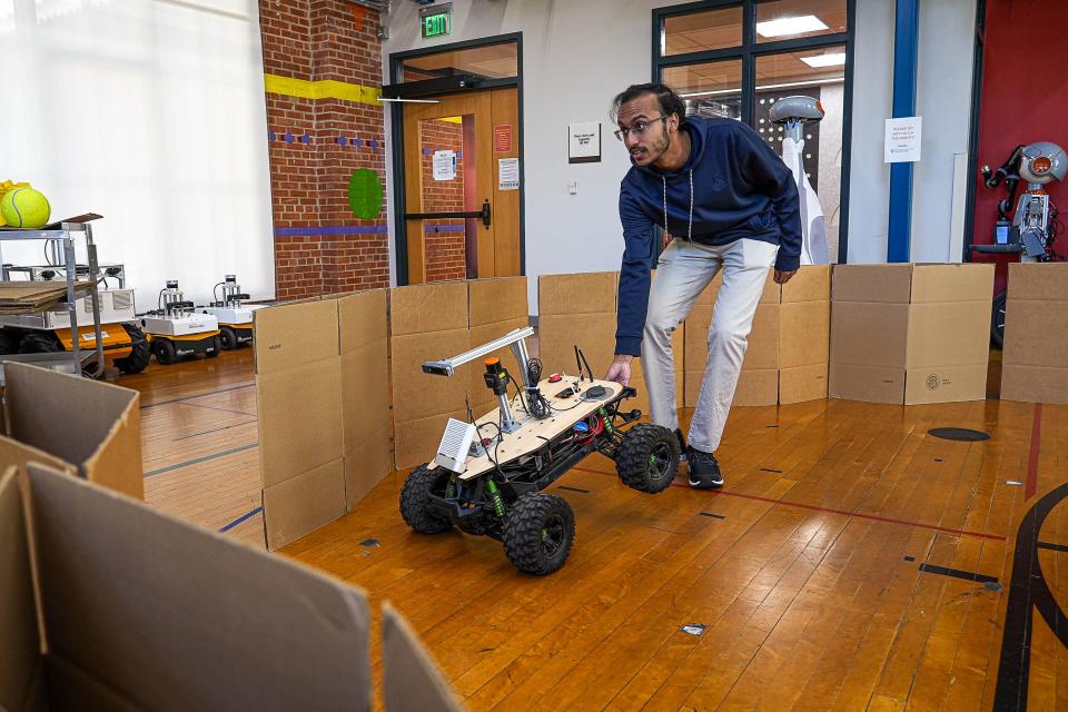 Rahul Menan, a first-year master's student, repositions the off-roading Alpha Truck robot in a Texas Robotics lab.