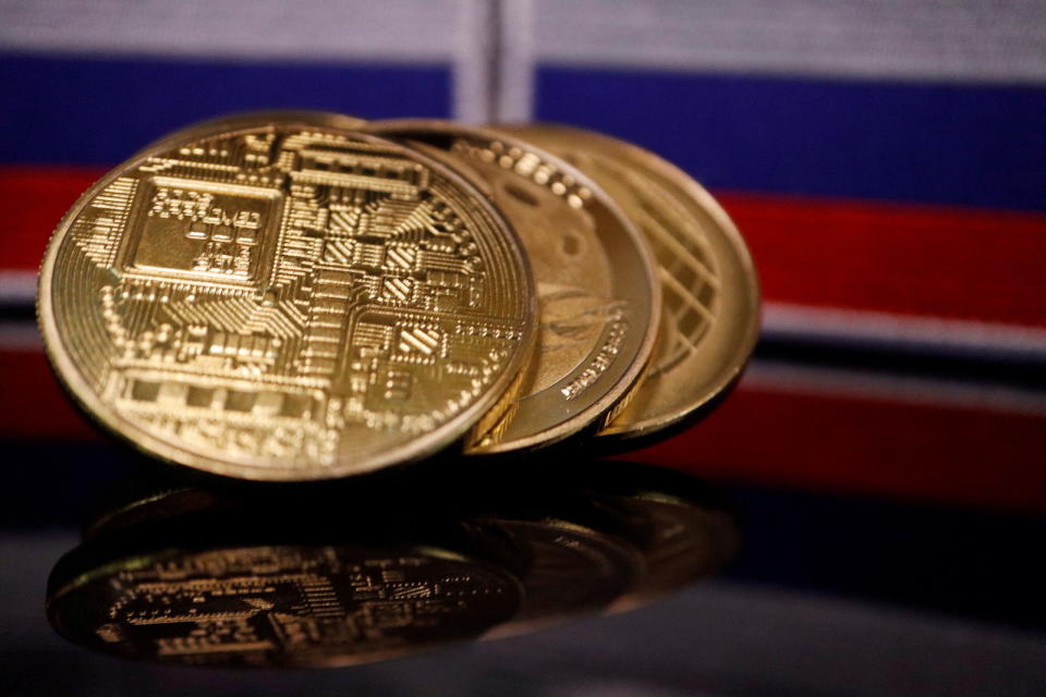 Representations of cryptocurrencies are displayed in front of Russian flags in this picture illustration taken March 4, 2022. REUTERS/Florence Lo/Illustration