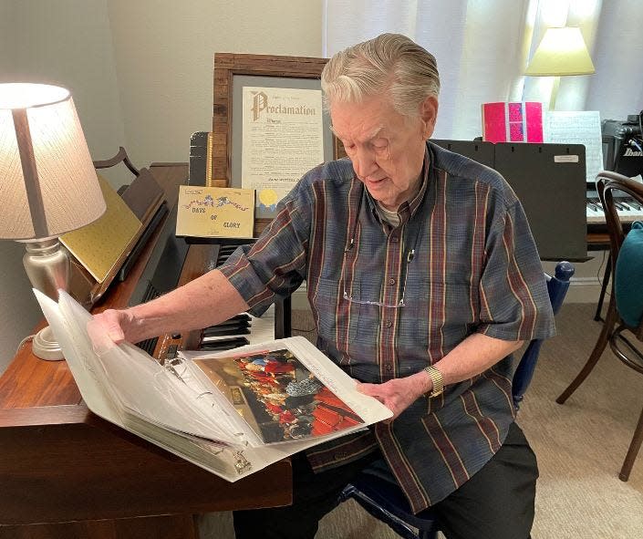 Former Alliance High School band director John Weitzel Sr., who turned 99 on Thursday, looks through pictures and other gifts he received from band alumni at his home in Kalamazoo, Michigan.