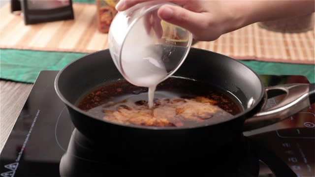 Pouring cornflour water into sauce in pan