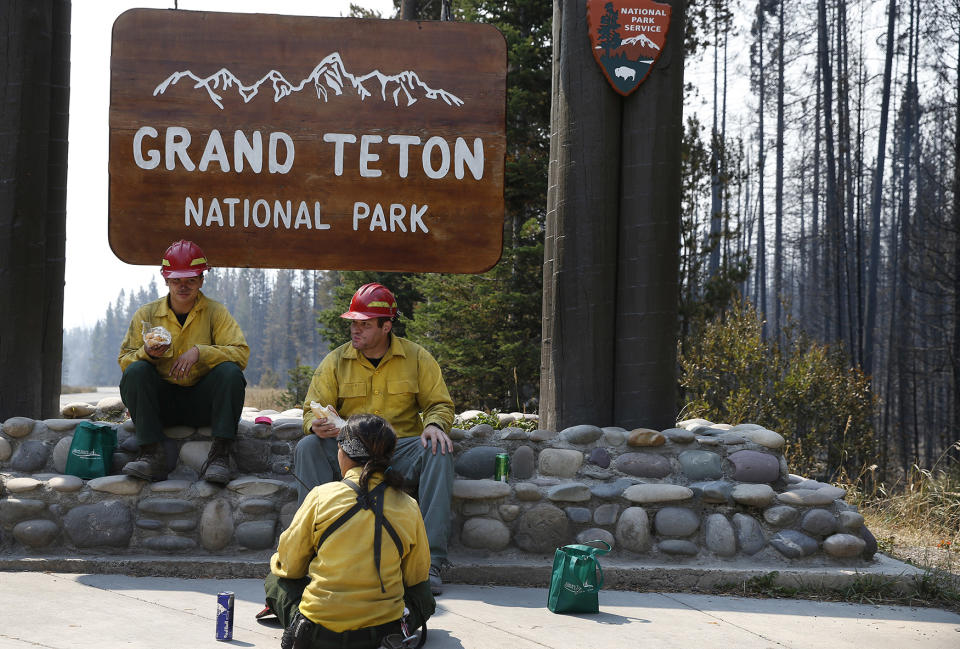 <p>Firefighters JJ Hawkinson, left, Brandon Bishop Parise, and Vanessa Aldrich, out of Ely, Nevada, take a lunch break while working on the Berry Fire in Grand Teton National Park, Wyo., Aug 25, 2016. Thursday, Aug 25, 2016 marks the 100th anniversary of the US National Park Service. (AP Photo/Brennan Linsley) </p>