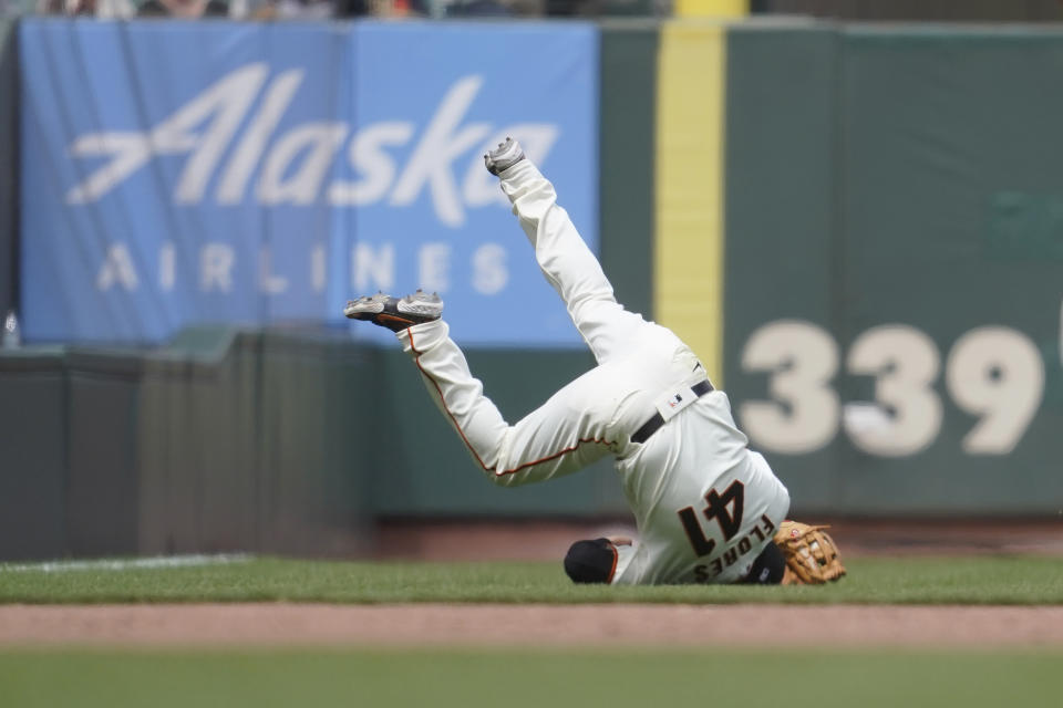 San Francisco Giants third baseman Wilmer Flores falls backward after catching a fly ball hit by Los Angeles Dodgers' Cody Bellinger during the seventh inning of a baseball game in San Francisco, Sunday, June 12, 2022. (AP Photo/Jeff Chiu)