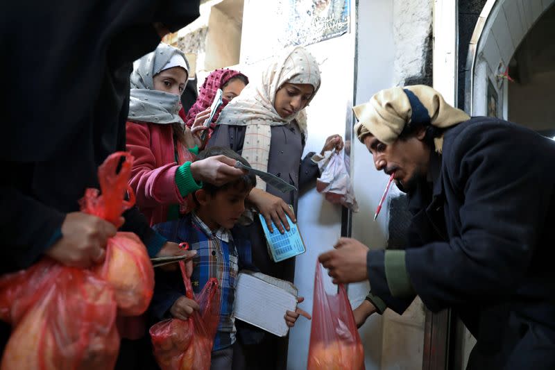 FILE PHOTO: A woman and children receive food donations from a charity kitchen in Sanaa, Yemen