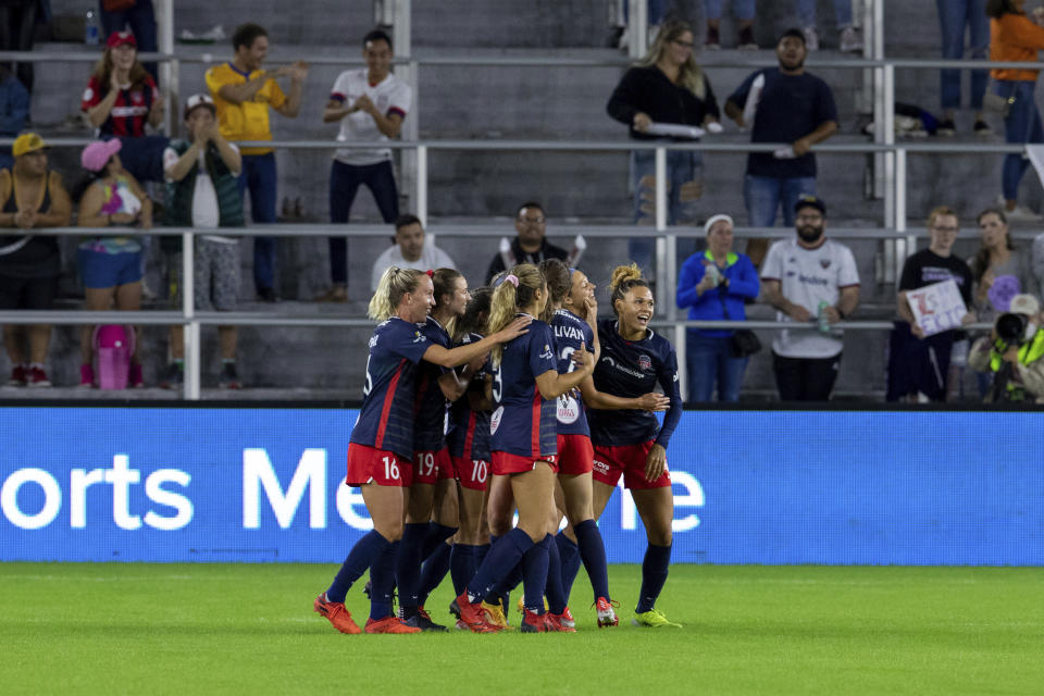 Members of the Washington Spirit embrace after their team scored a goal during the first half of an NWSL soccer match in Washington, on Saturday, Oct. 9, 2021. (AP Photo/Amanda Andrade-Rhoades)