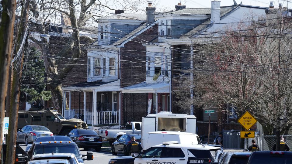 Police surround a home in Trenton, New Jersey, where they believed the man suspected of killing three people was on Saturday. - Matt Rourke/AP