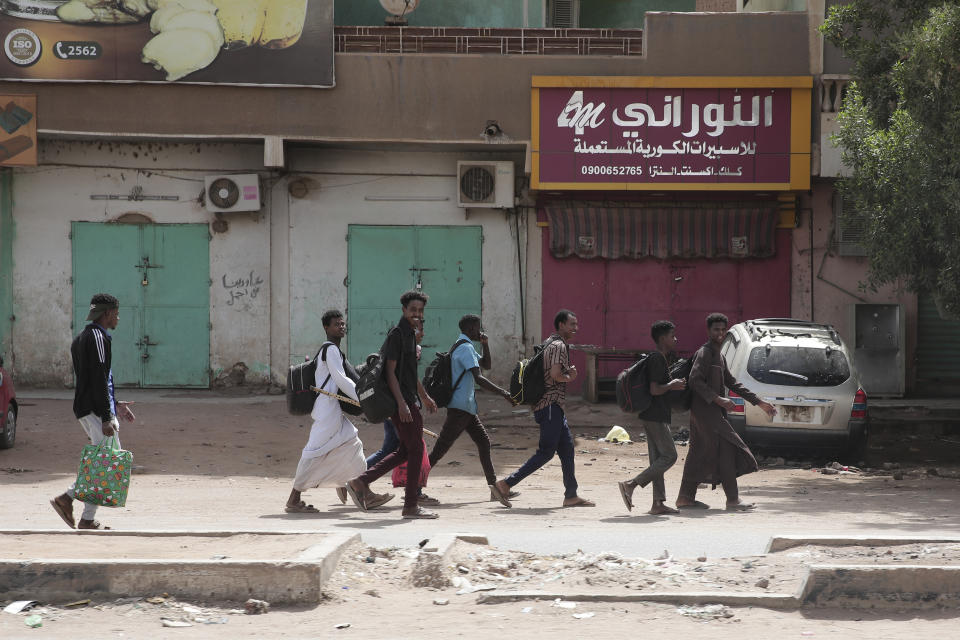 People walk past shuttered shops in Khartoum, Sudan, Monday, April 17, 2023. Sudan's embattled capital has awoken to a third day of heavy fighting between the army and a powerful rival force for control of the country. Airstrikes and shelling intensified on Monday in parts of Khartoum and the adjoining city of Omdurman. (AP Photo/Marwan Ali)