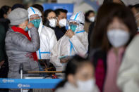 Travelers wearing protective suits, face masks, and goggles stand in line to check in for a Cathay Pacific flight to Hong Kong at Beijing Capital International Airport in Beijing on Jan. 15, 2023. A hoped-for boom in Chinese tourism in Asia over next week’s Lunar New Year holidays looks set to be more of a blip as most travelers opt to stay inside China if they go anywhere. (AP Photo/Mark Schiefelbein)