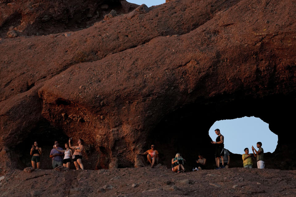 Hikers watch the sunset at Papago Park, Friday, July 14, 2023 in Phoenix. Phoenix hit 112 degrees on Friday, marking the city's 15th consecutive day of 110 degree-plus temperatures and putting it on track to beat the longest measured stretch of such heat. The record is 18 days, recorded in 1974. Desert residents accustomed to scorching summers are feeling the grip of the heat wave hitting the Southwest this week.(AP Photo/Matt York)