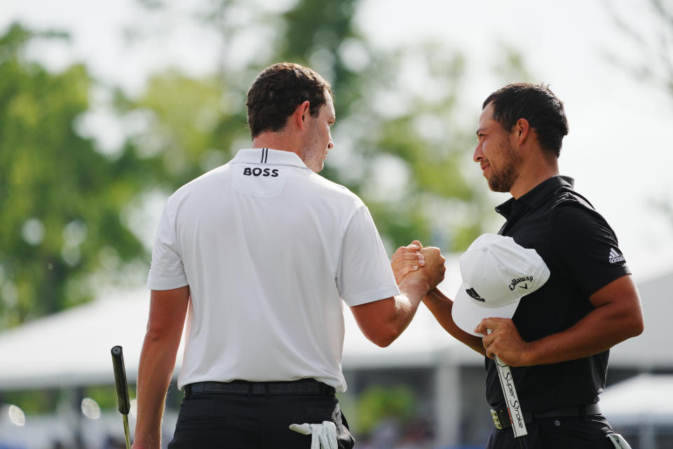 Xander Schauffele (right) embraces Patrick Cantlay (left) on the 18th green during the final round of the Zurich Classic of New Orleans golf tournament. Mandatory Credit: Andrew Wevers-USA TODAY Sports