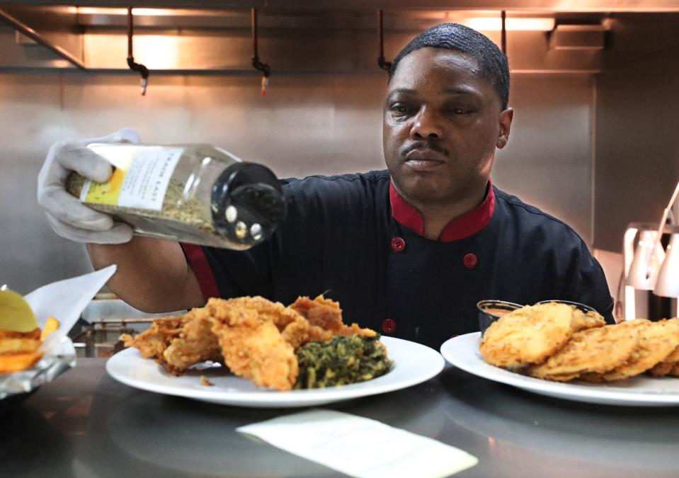 Chef James Tyler sprinkles seasoning on the fried catfish in the kitchen of Sweetbeats Sports & Soul Food Karaoke Bar in Akron.
