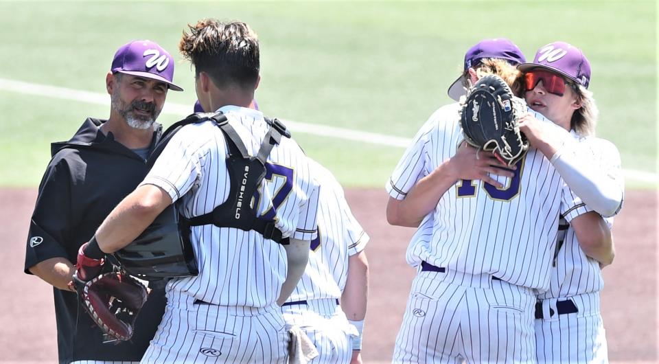 A Wylie player hugs starter pitcher Brooks Gay before he leaves the mound in the seventh inning for a relief pitcher while coach Grant Martin talks to catcher Landon Williams.