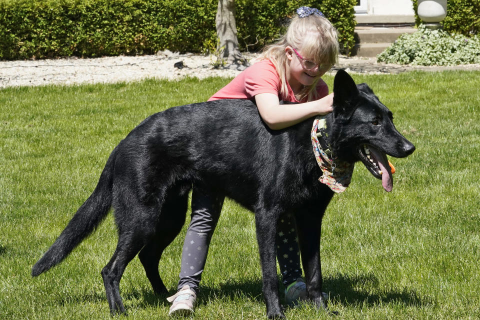 Lyra Christensen hugs her dog, Otto, Thursday, May 13, 2021, in Akron, Ohio. Anti-abortion activists say 2021 has been a breakthrough year for legislation in several states seeking to prohibit abortions based on a prenatal diagnosis of Down syndrome. Opponents of the bills, including some parents with children who have Down syndrome like Lyra's mother Holly, argue that elected officials should not be meddling with a woman’s deeply personal decision on whether to carry a pregnancy to term after a Down syndrome diagnosis. (AP Photo/Tony Dejak)