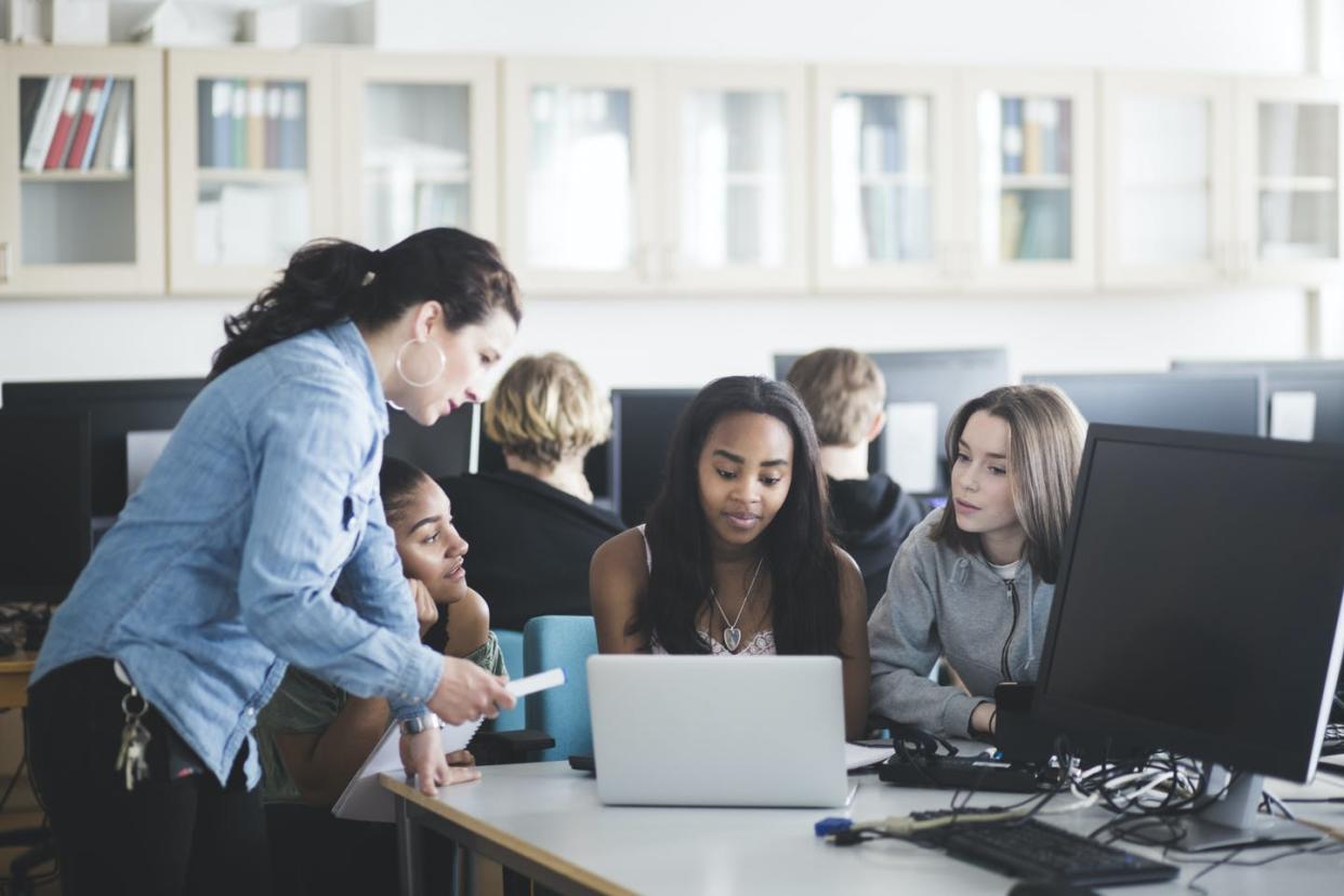 <span class="caption">A teacher works with students in a computer lab.</span> <span class="attribution"><a class="link " href="https://www.gettyimages.com/detail/photo/mature-teacher-assisting-female-students-using-royalty-free-image/1055844022" rel="nofollow noopener" target="_blank" data-ylk="slk:Maskot via Getty Images;elm:context_link;itc:0;sec:content-canvas">Maskot via Getty Images</a></span>