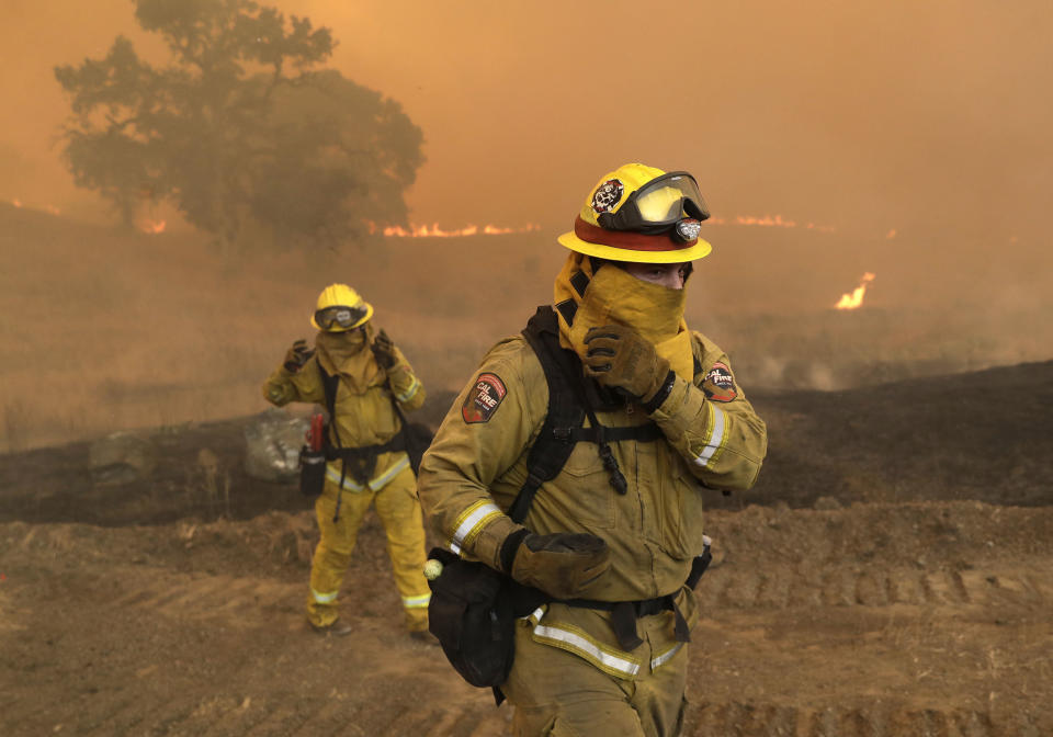 Firefighters with Cal Fire Mendocino Unit cover themselves from smoke and ash created by an advancing wildfire in Lakeport.&nbsp;