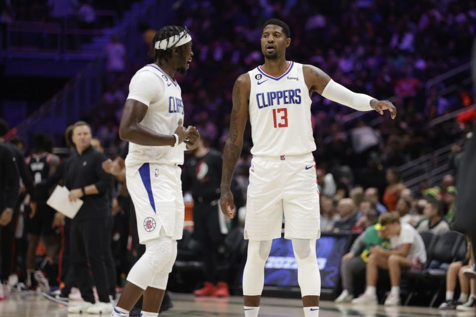 Paul George and Reggie Jackson talk on the court.