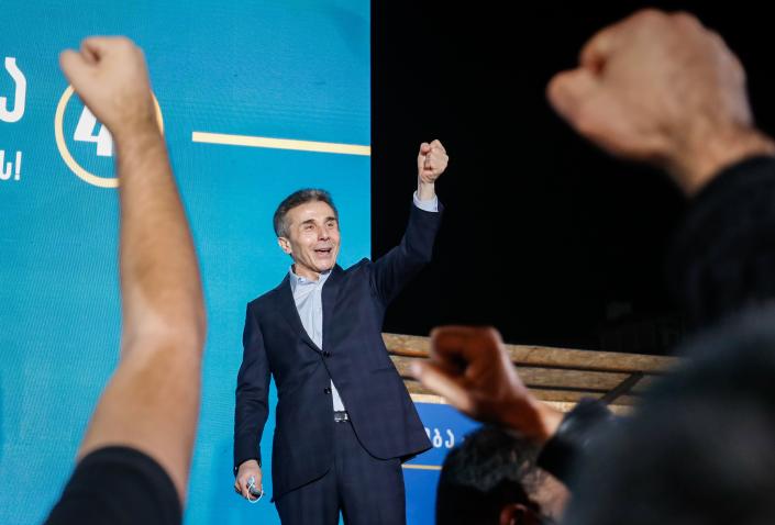 Bidzina Ivanishvili raises his fist in the air, as do his supporters.